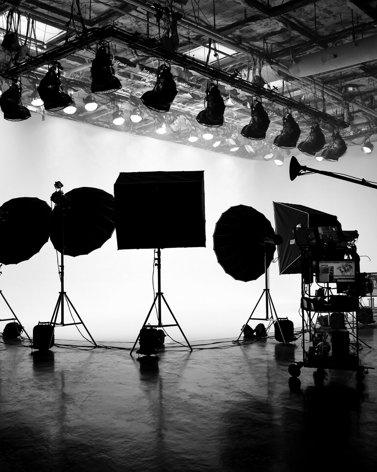 Monochromes High-End-Filmstudio: Softboxen und Scheinwerfer-Rig vor einer strahlend hellen Hohlkehle, Regie-Wagen am Rand